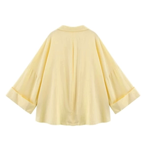 Detailed back view of a light yellow oversize linen blouse with center pleat and wide cuffs