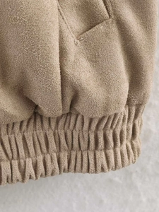 Detail of camel faux suede jacket showing ribbed hem and textured fabric finish