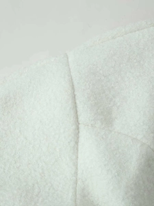 Close-up of white plush wool-like fabric texture and detailed stitching on autumn jacket