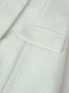 Close-up of cream white wool blend coat featuring soft faux fur texture and flap pocket detail
