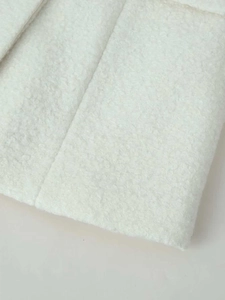 Close-up of white bouclé fleece fabric texture and stitching on a stand collar jacket