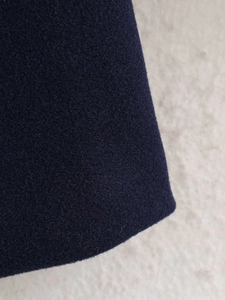 Detailed close-up showing the premium navy wool fabric texture and hem of the jacket