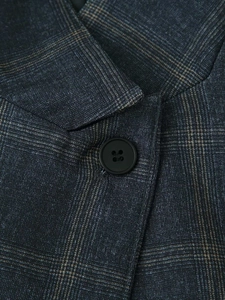 Detailed view of the peak lapel and dark button on a blue plaid blazer jacket