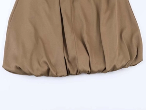 Detail of brown midi skirt featuring gathered bubble hem and smooth pleated fabric texture