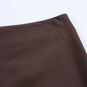 Détail de la taille d'une jupe en satin marron foncé montrant la texture fine du tissu