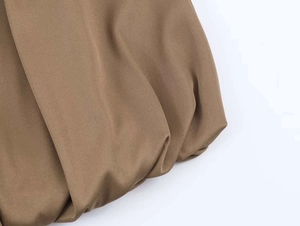 Detailed close-up of the gathered hem design on a loose khaki midi skirt with twill texture