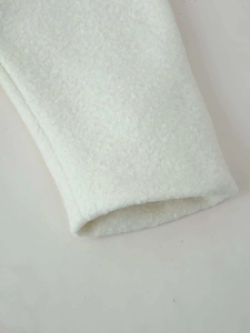 Detailed close-up of soft white fleece fabric texture on a stylish wool jacket sleeve