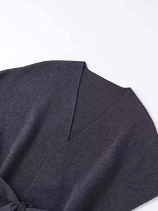 Détail de maille gris foncé avec col en V, ceinture nouée et texture douce et fine