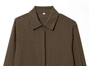 Detailed close-up of brown checkered shirt collar with size S label on white background
