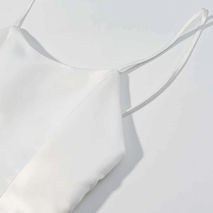 Close-up of white satin dress showing thin shoulder straps and glossy silk texture