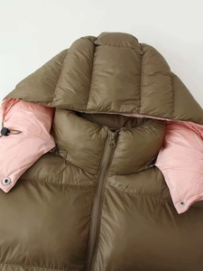 Detail of olive green puffer jacket with pink lining showing zipper and snap buttons