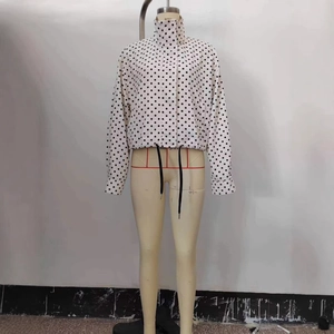 Loose white long-sleeved jacket with black polka dots and drawstring hem on mannequin
