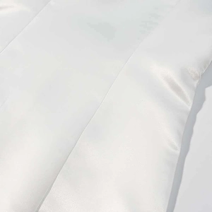 Detail of white satin dress showing fabric luster and side seam stitching texture