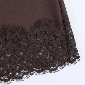 Détail de l'ourlet en satin marron foncé avec dentelle florale délicate