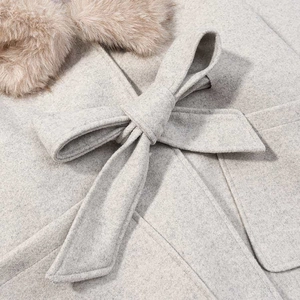 Detail of oatmeal wool coat featuring faux fur collar and waist tie bow accents