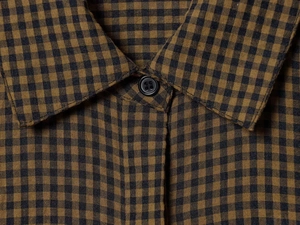 Detailed close-up of brown and black gingham shirt collar with a classic round button