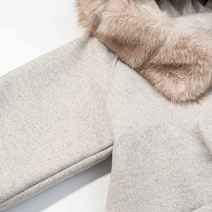 Detail of grey wool coat featuring a soft brown faux fur collar and textured fabric