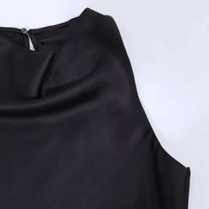Dettaglio della tunica in raso nero con scollo a cappuccio e chiusura con bottone