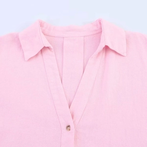 Detail of pink striped short sleeve shirt featuring a V-neckline and a dark button