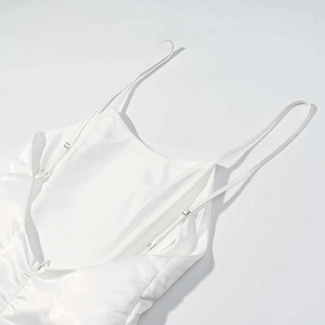 Detailed macro view of ivory satin dress showing adjustable silver strap buckles and texture
