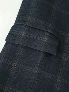 Macro shot of glen check fabric and flap pocket detail on classic dark navy blazer
