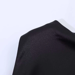 Dettaglio del tessuto in raso di seta nero con trama fine e leggeri riflessi lucidi