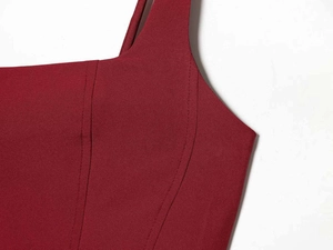 Detail shot of square neckline and sturdy straps on burgundy satin dress with fine stitching