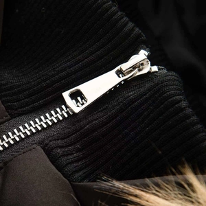 Gros plan sur la veste d'hiver avec fermeture éclair trapèze en métal et tricot noir nervuré