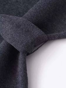 Détail macro du tissu en maille gris foncé montrant la texture et le nœud élégant