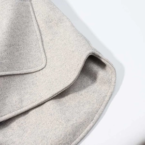 Detailed macro view of light gray wool blend coat fabric with fine stitching and pocket edge