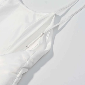 Detail of adjustable thin shoulder straps on a white satin sleeveless dress