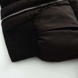 Détail de la fermeture éclair argentée et poignet côtelé sur veste matelassée noire
