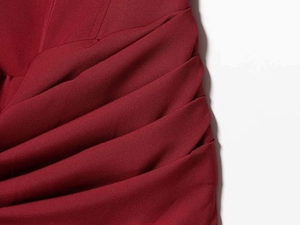 Detail showing the burgundy satin fabric with elegant draping and pleated layering