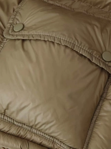 Detailed close-up of olive green quilted winter jacket with metal snap button pocket