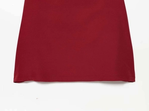 Detailed close-up of the stitched hem on a dark red satin pleated fishtail dress