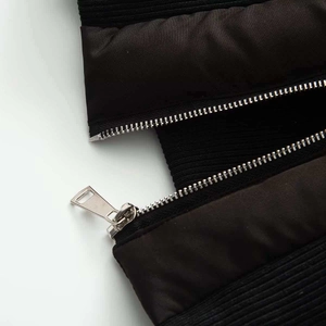 Gros plan détaillé de la fermeture éclair métallique et du tissu noir brillant d'une doudoune