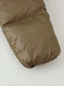 Close-up of olive green quilted winter jacket showing glossy fabric and detailed stitching