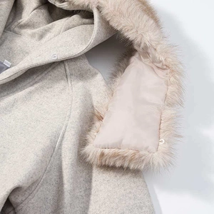 Close-up of oatmeal wool coat featuring a soft faux fur trim on the hood detail