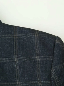 Detailed close-up showing the fine plaid wool blend texture on the grey suit jacket shoulder