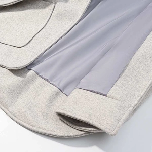 Close-up of wool texture and smooth lining detail on the hooded cape coat