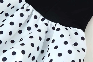 Detail view of the pleated waist seam and polka dot fabric on the black summer dress