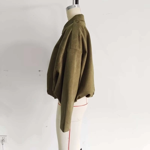Detailed side view of a dark green suede bomber jacket on a white mannequin torso