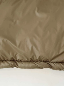 Detail of olive green puffer jacket showing the stitched hem and smooth quilted fabric