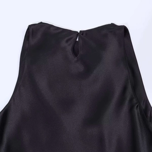 Dettaglio del top nero in raso senza maniche con scollo a goccia e chiusura a bottone