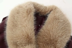 Détail d'une veste en cuir bordeaux avec un col amovible en fausse fourrure épaisse