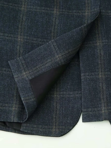 Close-up of navy plaid blazer fabric texture with inner lining and hem slit details