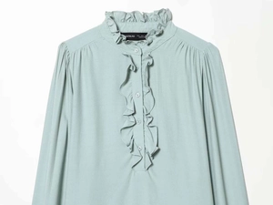 Close-up of mint green chiffon shirt featuring delicate ruffle edges and pleated collar