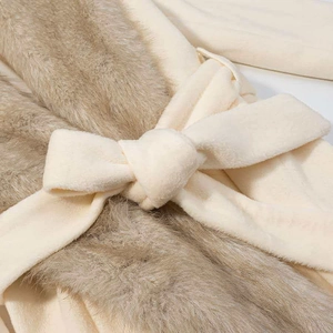 Detailed view of the waist tie and brown faux fur trim on the cream coat