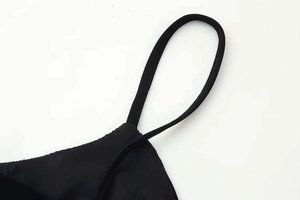 Detail of thin spaghetti straps and stitching on a black sleeveless V-neck polka dot dress