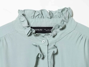 Detail of mint green blouse with ruffled collar and matching buttons on chiffon fabric